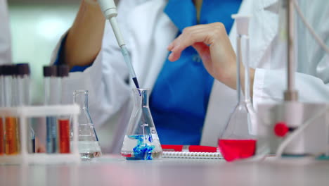 Female-scientist-pouring-reagent-in-lab-flask.-Scientist-doing-chemical-reaction